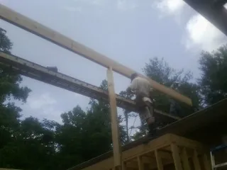 Carpenter setting a ridge beam over a new addition frame — Ice Dam Removal by Roofing Brothers in Calder