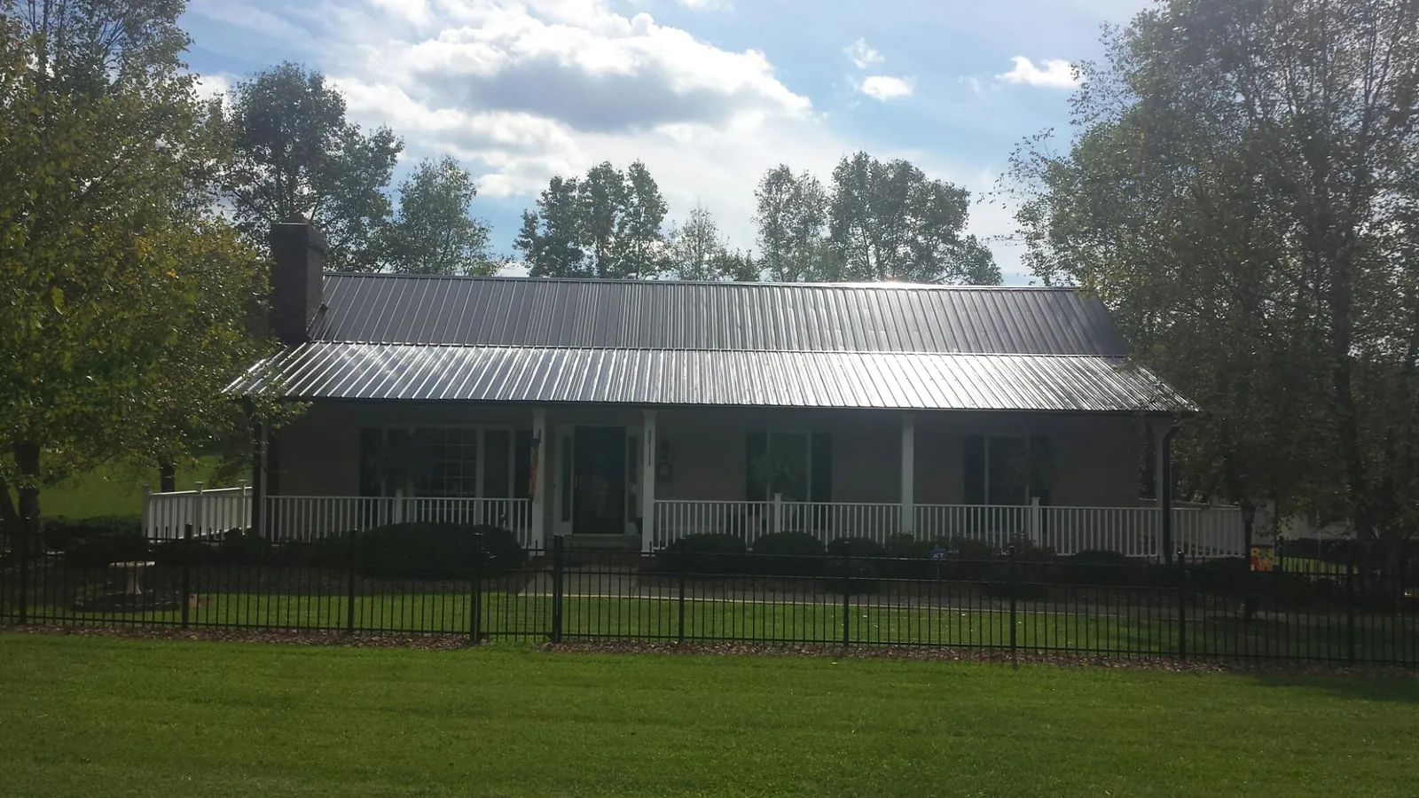 Gray metal roof on a brick ranch with a full width front porch — Gutter Guard Installation work by our crew in Calder