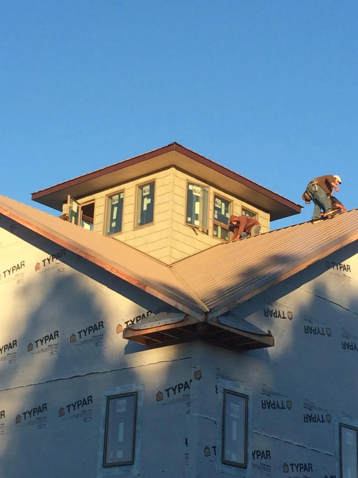 Roofers working around a rooftop cupola on a new metal roof at sunset — Roof Waterproofing in Calder by Roofing Brothers